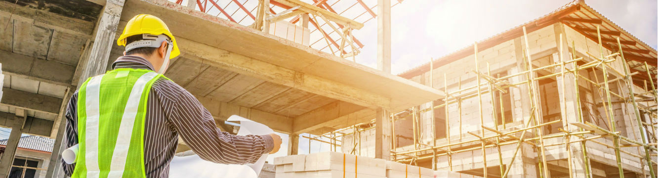 Un homme lit un plan sur un chantier